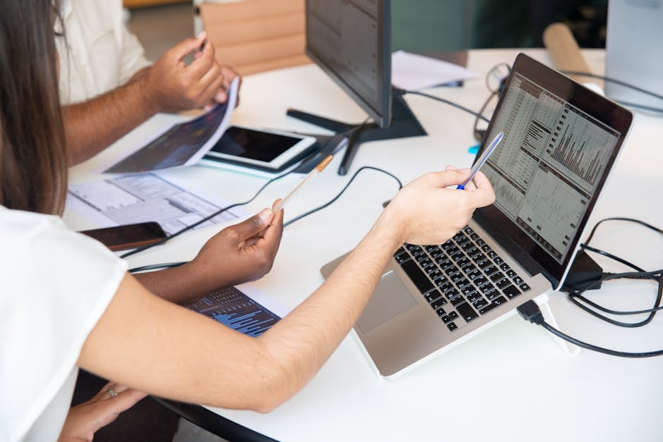 Professionals analyzing data charts on a laptop in an office setting, collaboratively discussing insights.